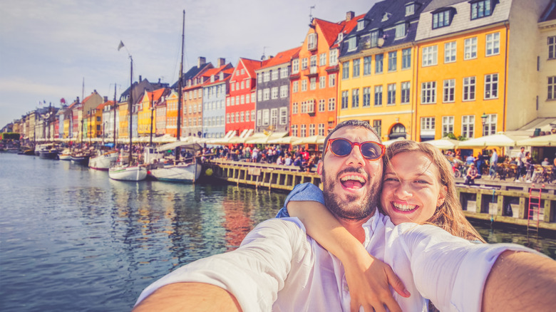 Smiling couple take a selfie at Nyhavn, Copenhagen, Denmark