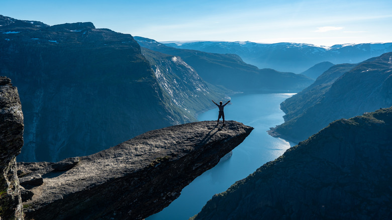 Person posing on rock over dramatic fjord views in Norway