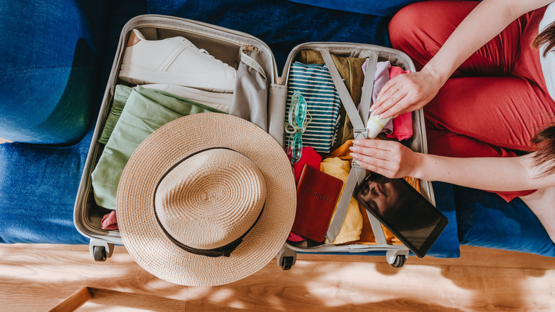 Traveler packing carry-on suitcase neatly