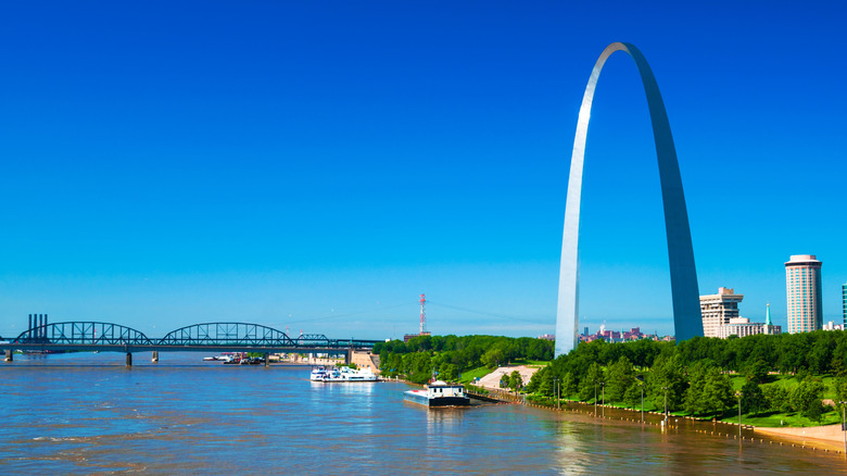 The Gateway Arch and boats on the Mississippi River, with a bridge across the river visible ahead