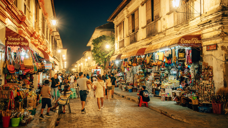 Cobblestone street with vendors and shops at night in Vigan City in the Philippines.