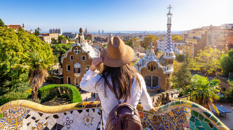 Woman with hat and backpack looking at view of park in Barcelona