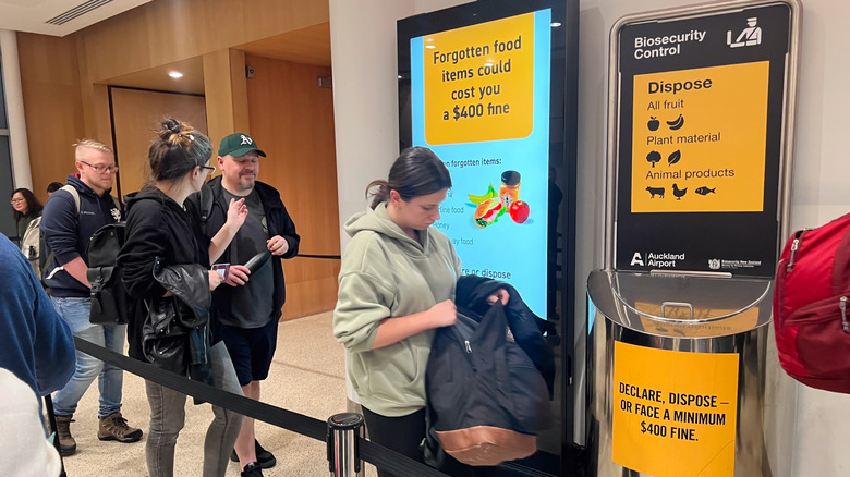 People passing a sign warning of a $400 fine if they take food into New Zealand