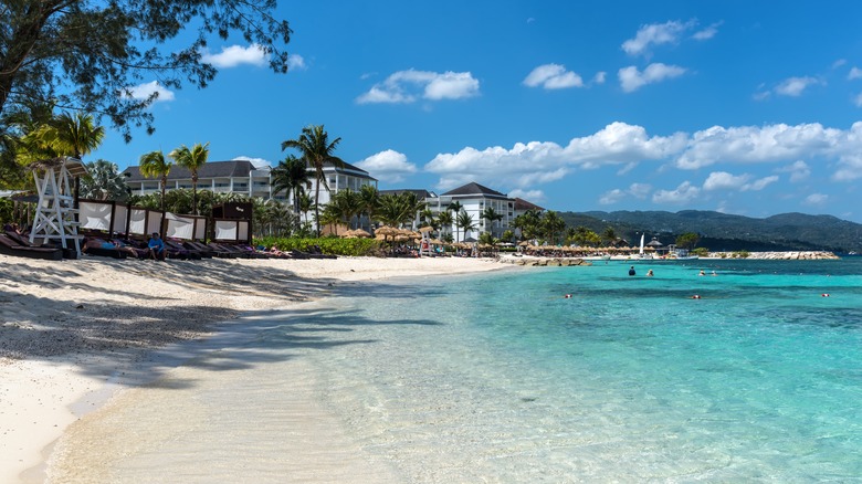A beach view with crystal clear water and buildings along the shore