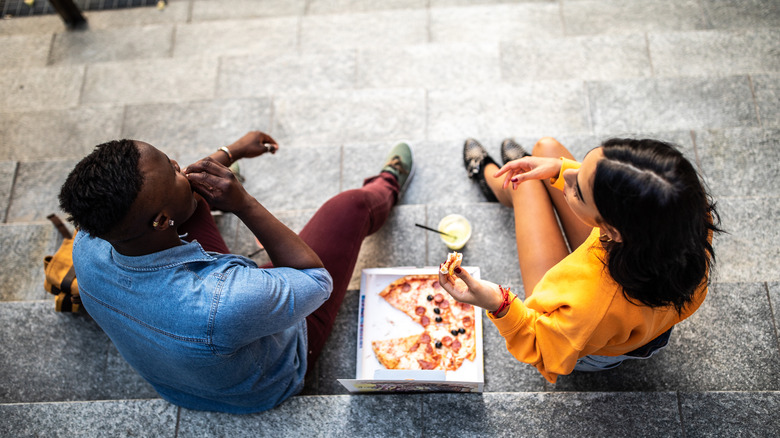 Couple eating pizza on steps