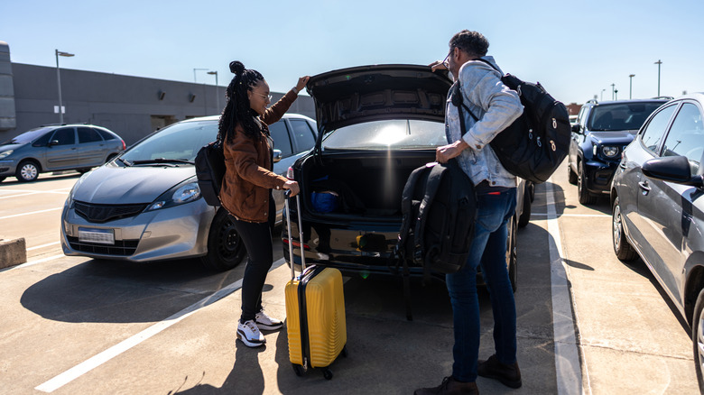 Couple removing items from their car in airport parking