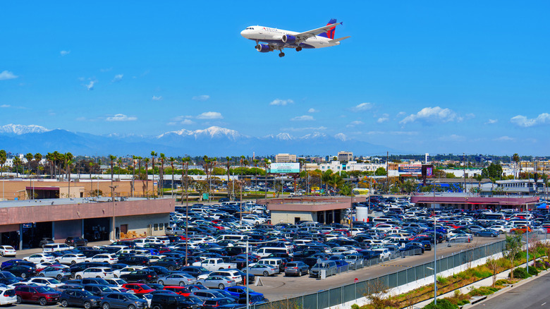 Parking lot full of cars with an airplane flying overhead in Los Angeles, California