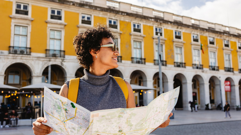 Smiling tourist looking at map while traveling Europe