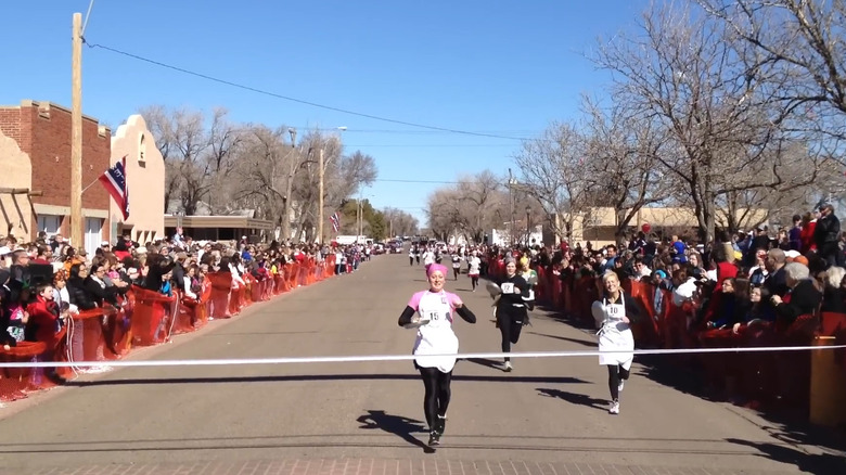 Women running with skillets in the Pancake Race in Liberal, Kansas