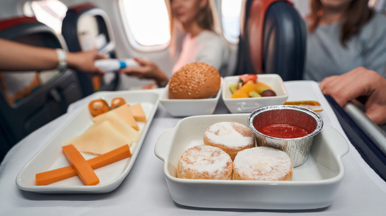 Tray of airline caterign food including cheese, bread and cakes