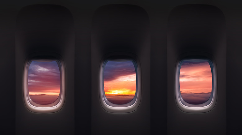 Three airplane windows with view of sunset