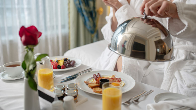 Person eating a meal from a hotel's room service menu