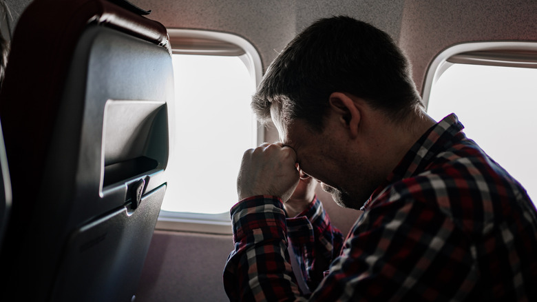 Man rubbing his eyes on a flight