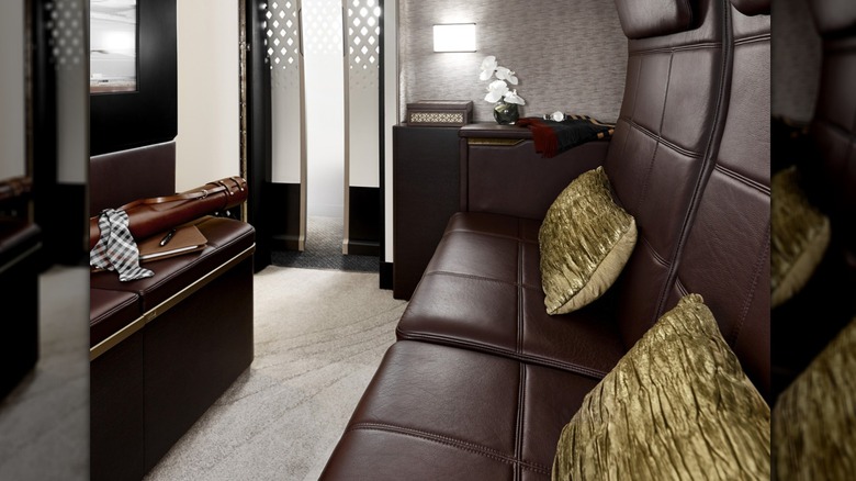 the living room of Etihad's The Residence on the A380, with a sofa and ottomans