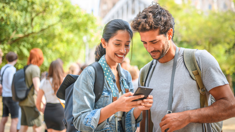 A smiling couple consulting their phone while traveling