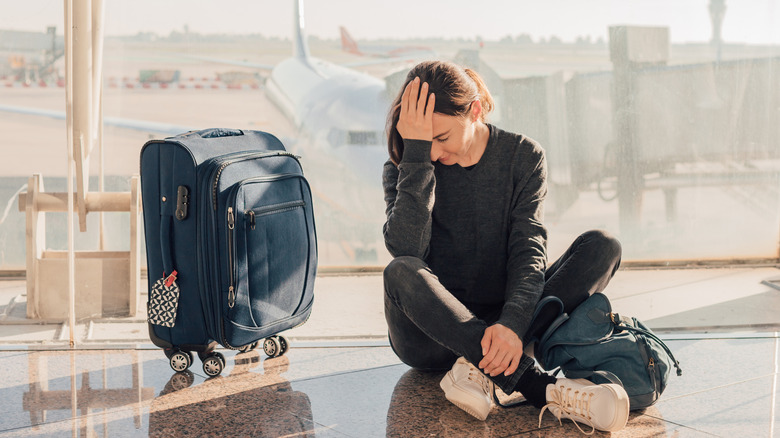 Woman sits with her head in her hand in airport terminal