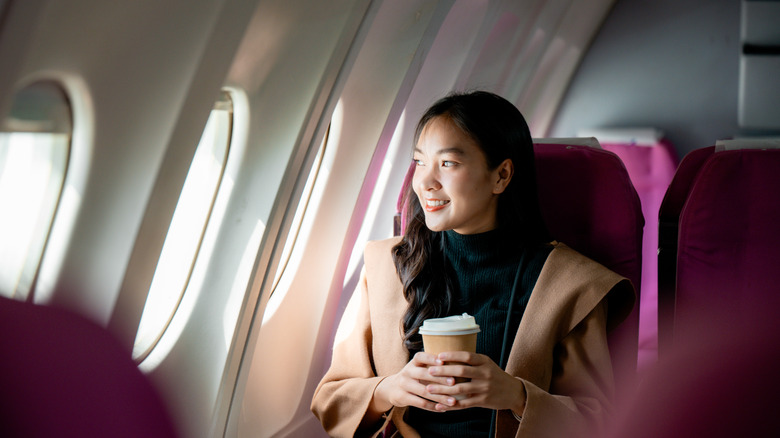 woman relaxes into her seat and smiles after making it onto her flight