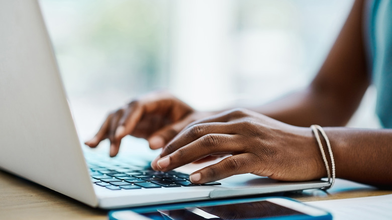Closeup of a woman's hands typing on laptop