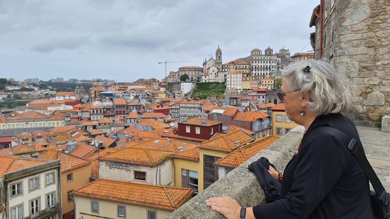 A retired woman looking over a Portuguese city skyline