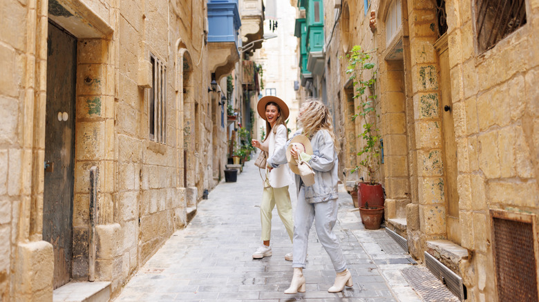 Two women holding hands and laughing in the streets of Valletta, Malta