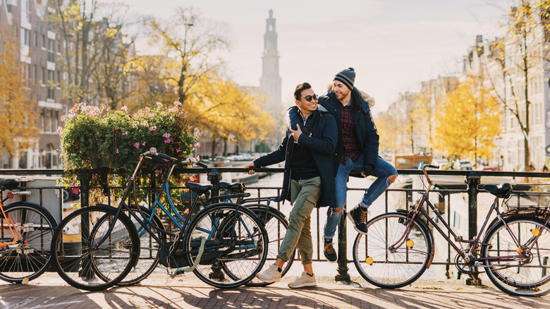 Two men embracing for a photo in front of the canals in Amsterdam