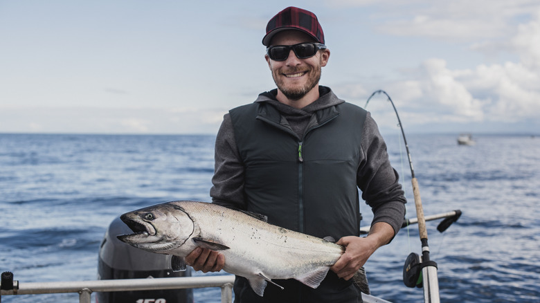Smiling sports fisherman holding a salmon in Campbell River, British Columbia.