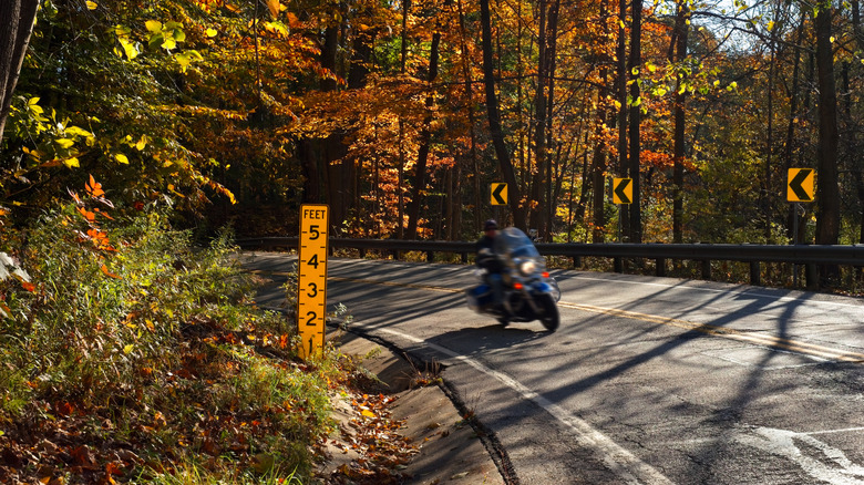 A motorcyclist rounds a curve on a winding countryside road in Ohio with fall leaves