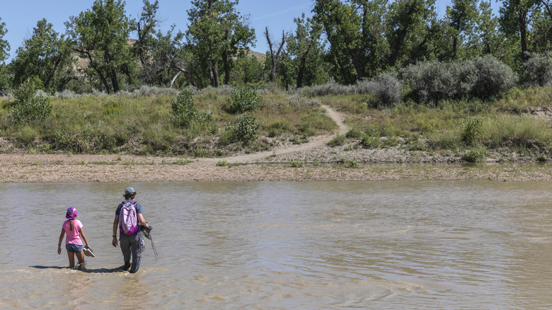Father and daughter wading across the river in the North Dakota wilderness