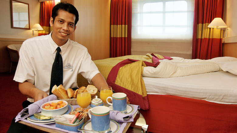 Smiling cruise server holding a breakfast tray