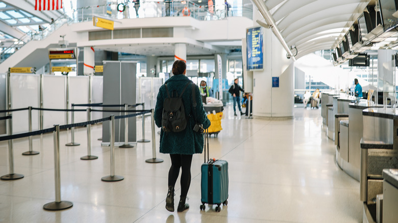 Female traveler pushing a suitcase through the airport