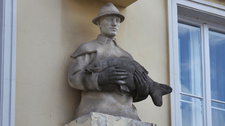 Sculpture of a man holding a carp on an old house in Trebon in the Czech Republic
