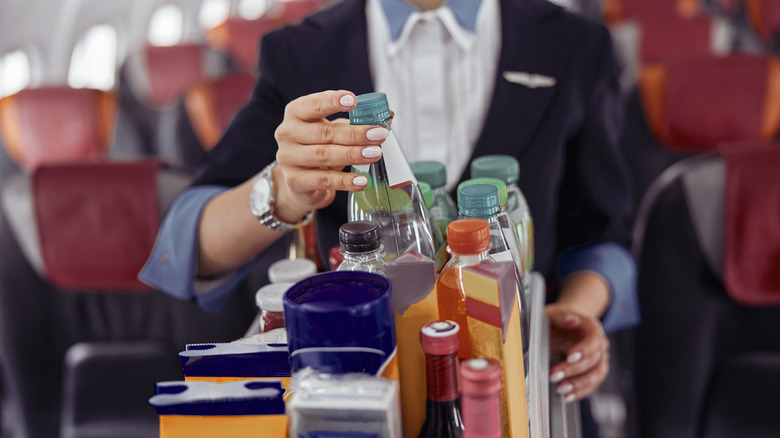 A flight attendant grabbing a bottle of water from the on board serving trolley
