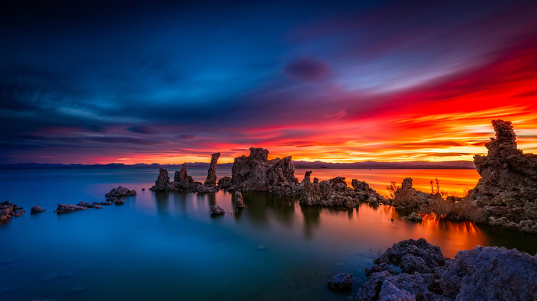 Bold, colorful sunrise over Mono Lake's tufa formations, oranges and reds reflecting in the deep blue water