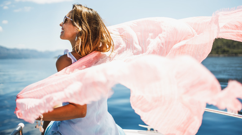Woman on a boat with a pink scarf floating in the breeze