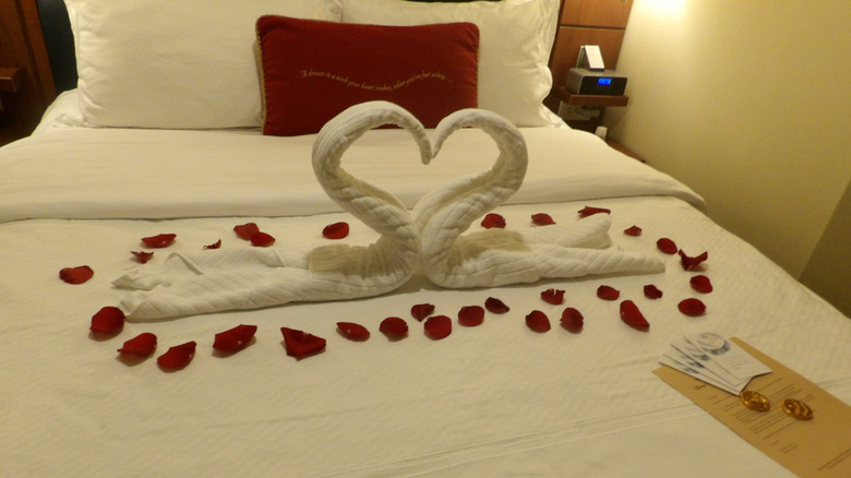 A cruise ship stateroom bed covered in rose petals