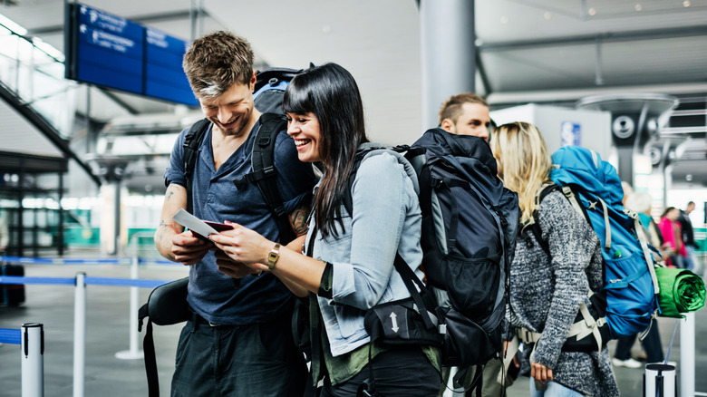 A couple at the airport with backpacks and travel documents.