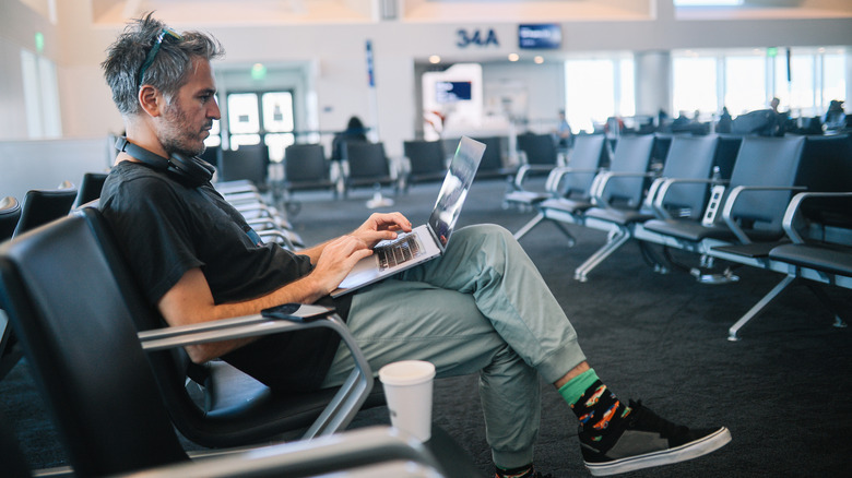 A man working on his lap top inside of an airport
