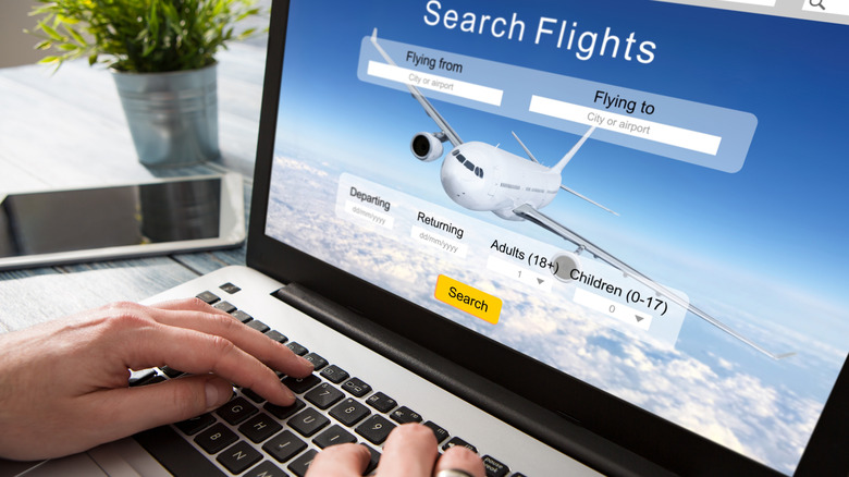 hands on keyboard, screen showing a flight search