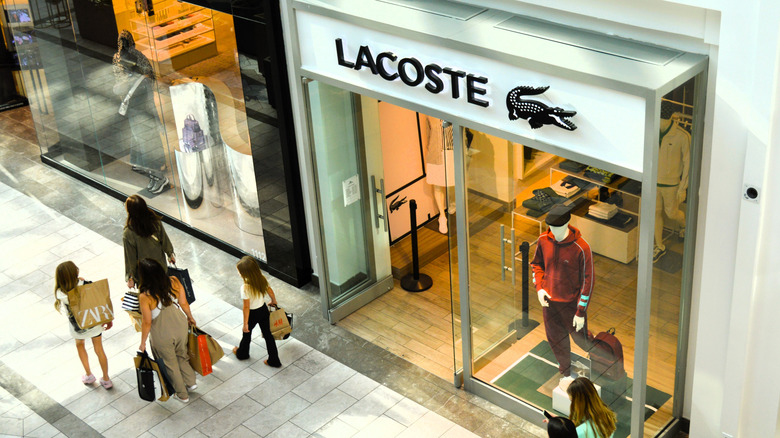 Shoppers carry bags past a Lacoste store in Scottsdale Fashion Square, Arizona