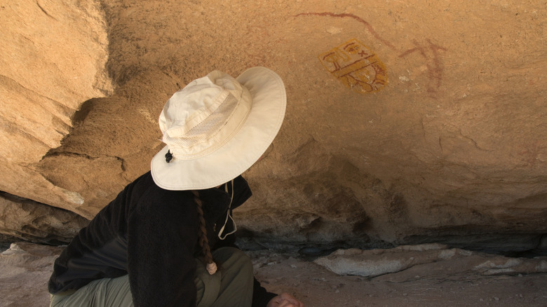 Woman with white hat looking at the pictographs in Hueco Tanks