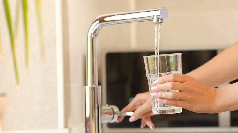 Someone pouring tap water into a glass