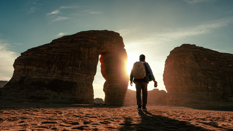 Hiker approaches a natural stone arch