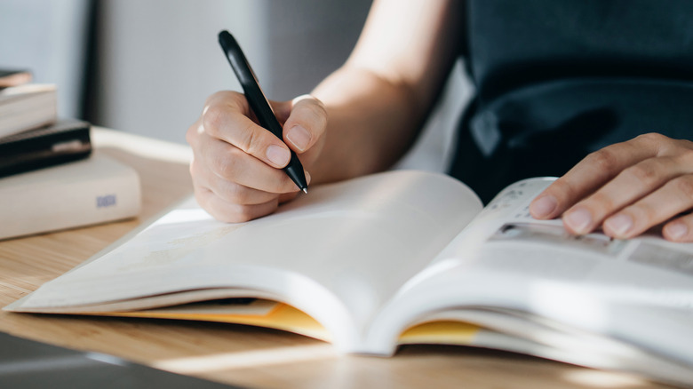 Person using a pen to write in a notebook