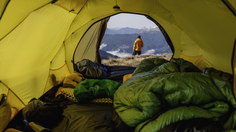 View of a person on a mountain range from inside a tent
