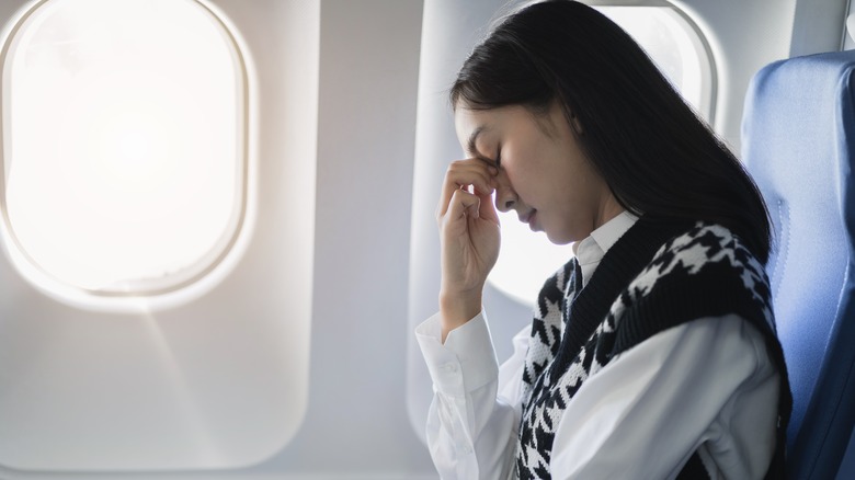 Traveler holding their nose while on a plane