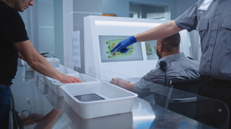TSA agent pointing to an ipad in the bin