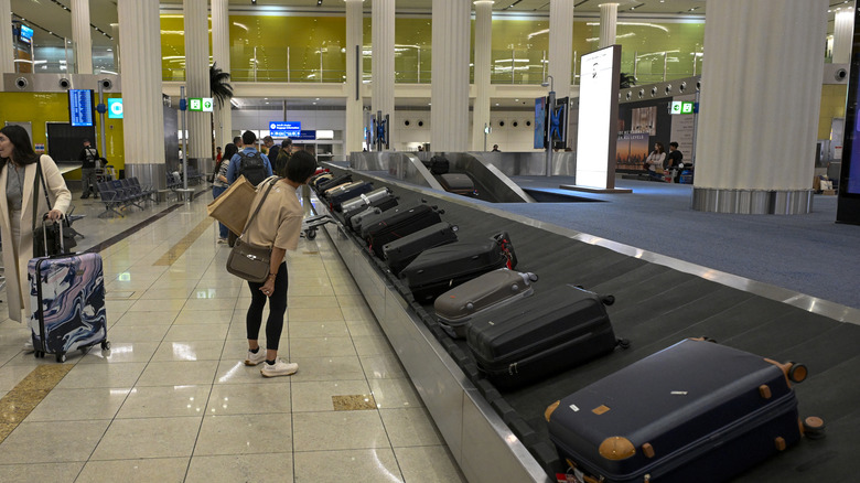 A passenger waits for their luggage to arrive on the carousel