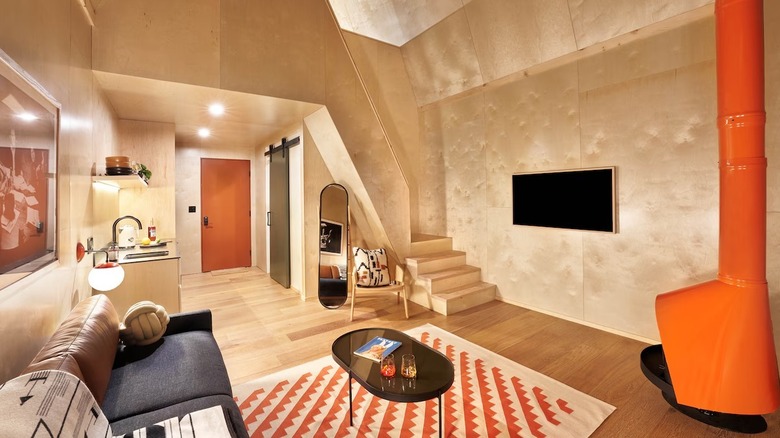 the interior design of the the A-frame cabins uses orange and green accents and geometric patterns to reflect 1970s aesthetics