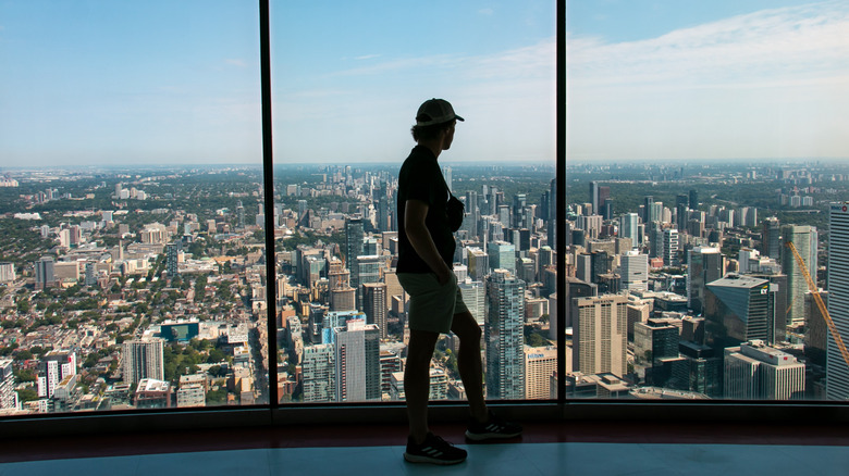 person standing inside the CN Tower by glass windows
