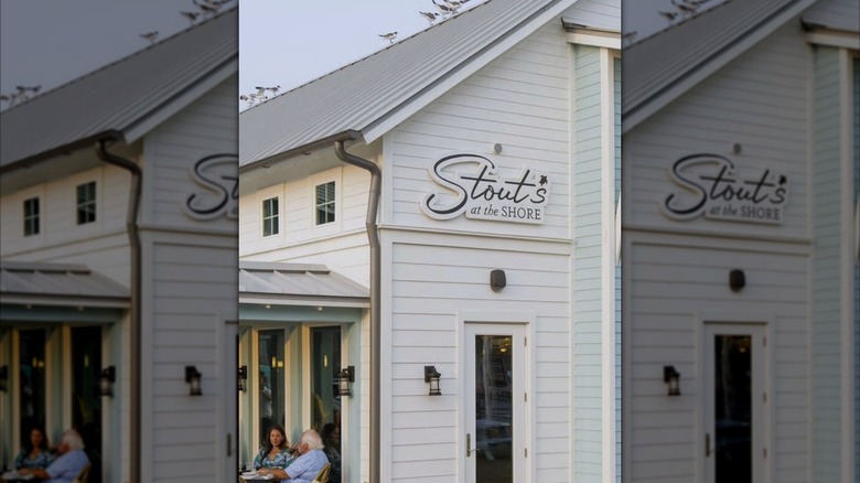White exterior of restaurant with people eating outside